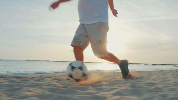 Man dribbelen op het strand bij zonsondergang — Stockvideo