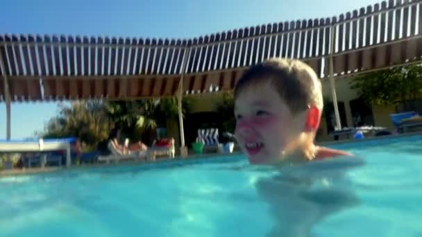 Gyermek élvezve úszás a kinti medencében — Stock videók