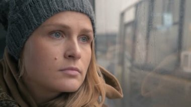 Woman staring through the wet bus window