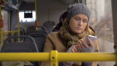 Young sad woman using smart phone in the bus