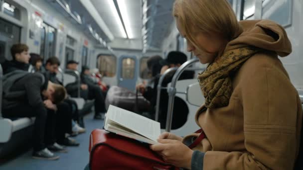 Mujer joven leyendo un libro en metro — Vídeos de Stock