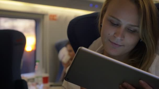 Женщина путешествует на поезде с планшетным компьютером — стоковое видео