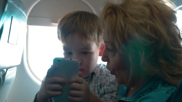 Grootmoeder en kleinzoon met cel in het vliegtuig — Stockvideo