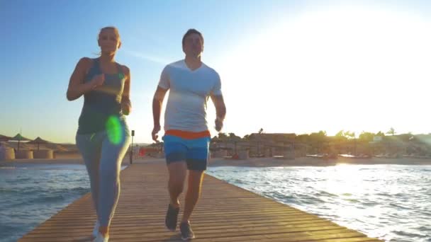 カップルが海の桟橋でジョギング — ストック動画