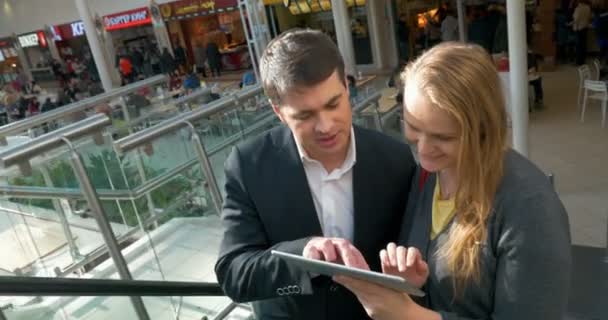 Pareja con Tablet PC en escalera mecánica — Vídeo de stock