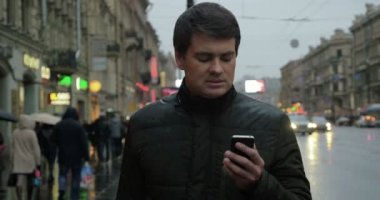 Adam sokakta akıllı telefon kullanıyor.
