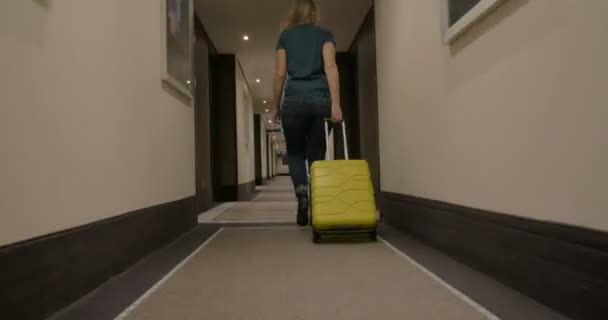 Frau läuft mit Rollkoffer die Hotelpassage entlang — Stockvideo