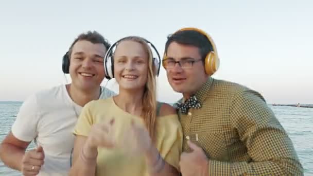 屋外のヘッドフォンで音楽を楽しむトリオを興奮 — ストック動画
