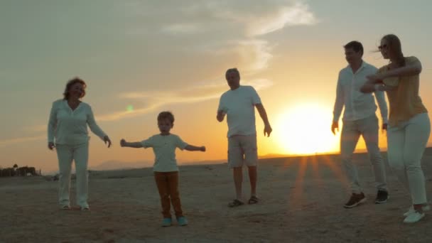 Gran familia feliz bailando en la playa al atardecer — Vídeo de stock