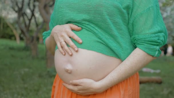 Беременная женщина обнимает живот на открытом воздухе — стоковое видео
