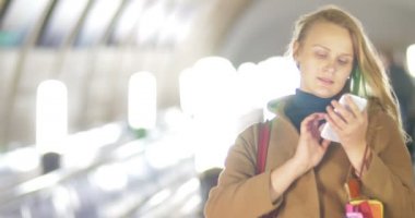 Woman with smart phone on subway escalator