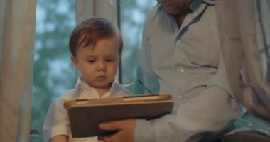 Baba ve küçük oğlu evde tablet bilgisayar kullanarak