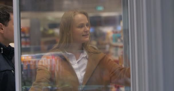 Joven pareja recogiendo comida del congelador de la tienda — Vídeo de stock