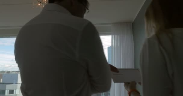 窓際でおしゃべりをしているパッドを持つビジネスマン — ストック動画