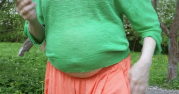 Беременная женщина сглаживает живот на открытом воздухе — стоковое видео