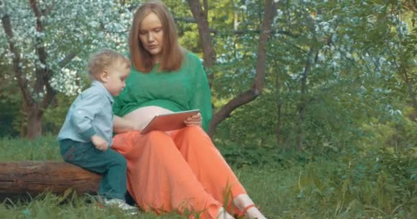 Embarazada madre e hijo con tableta PC al aire libre — Vídeo de stock