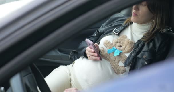 Kobieta w ciąży za pomocą inteligentnego telefonu w samochodzie — Wideo stockowe