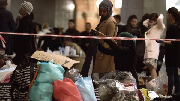 Сирийские беженцы слушают объявление в пункте сбора пожертвований на железнодорожной станции Копенгагена — стоковое фото