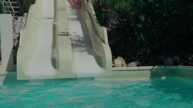 Yeşil şortlu genç, yaz eğlencesi için yavaş çekimde havuza atlıyor.