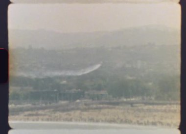 Orijinal arşiv görüntüleri Super 8 kamera görüntülerinde gözükür. Hava dublörlüğü yapan bir uçak sisli bir günde arka planda görünen uzak bir şehir silueti olan dumanlı bir iz bırakır.