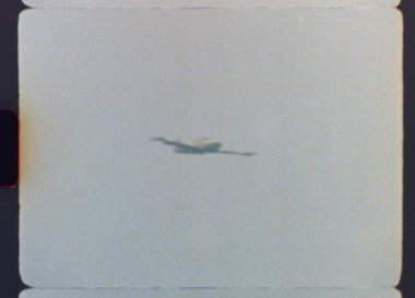 Orijinal, Otantik arşiv. 8mm 'lik bir askeri jet eğitmeninin bulanık gökyüzüne karşı tam bir fıçı dönüşü görüntüsü. Tahıl, ışık sızıntıları ve klasik ev yapımı film cazibesiyle.