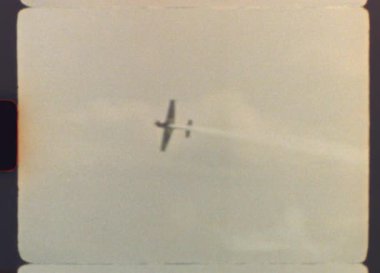 Orijinal Vintage Super 8 görüntülerinde yetenekli bir pilot nefes kesici bir akrobatik gösteri sergiliyor, bulutlu gökyüzüne karşı beyaz bir duman seli yaratıyor tarihteki heyecan verici bir hava gösterisinde