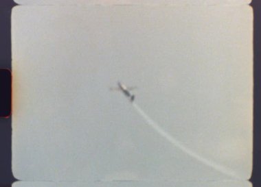 Otantik 8 mm 'lik film, bir hava gösterisi sırasında, havacılık becerisinin nostaljik ve geçmişe dönük bir gösterisini yakalayarak, cesaret gerektiren bir döngü manevrası yapan bir pervane uçağını gösteriyor.