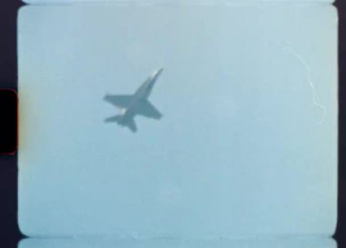 1980 'lerden ya da 1990' lardan kalma otantik Super 8mm film görüntüleri bir hava gösterisinde bir askeri jet uçağının akrobatik bir manevra yaptığını ve açık, puslu bir mavi gökyüzüne doğru uçtuğunu gösteriyor.
