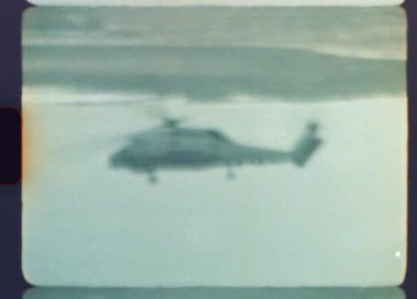Otantik Super 8mm film, bir devriye görevi sırasında denizin üzerinde alçaktan uçan askeri bir helikopter yakalar, tahıl, çizik ve ışık sızıntıları ile gerçek bir retro estetik sergiler.