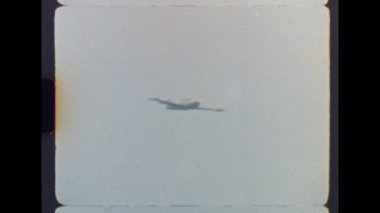 Orijinal, Otantik arşiv. 8mm 'lik bir askeri jet eğitmeninin bulanık gökyüzüne karşı tam bir fıçı dönüşü görüntüsü. Tahıl, ışık sızıntıları ve klasik ev yapımı film cazibesiyle.