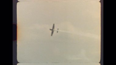 Orijinal Vintage Super 8 görüntülerinde yetenekli bir pilot nefes kesici bir akrobatik gösteri sergiliyor, bulutlu gökyüzüne karşı beyaz bir duman seli yaratıyor tarihteki heyecan verici bir hava gösterisinde
