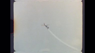 Otantik 8 mm 'lik film, bir hava gösterisi sırasında, havacılık becerisinin nostaljik ve geçmişe dönük bir gösterisini yakalayarak, cesaret gerektiren bir döngü manevrası yapan bir pervane uçağını gösteriyor.