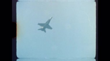 1980 'lerden ya da 1990' lardan kalma otantik Super 8mm film görüntüleri bir hava gösterisinde bir askeri jet uçağının akrobatik bir manevra yaptığını ve açık, puslu bir mavi gökyüzüne doğru uçtuğunu gösteriyor.