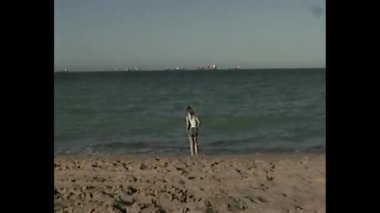 90 'lı yılların klasik video tarzında denizin kenarında genç bir kız.