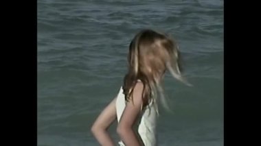 Saçları denize savrulan, klasik bantlı estetik bir kızın yan görüntüsü