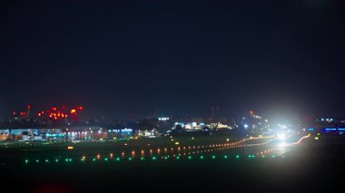 Pistten kalkan uçaklar gece boyunca renkli ışıklarla çevrili. Eğim kaydırma bulanıklığı kullanıyor.