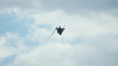 Taktik askeri helikopter, bulutların ve mavi gökyüzünün arka planına doğru uçuyor.