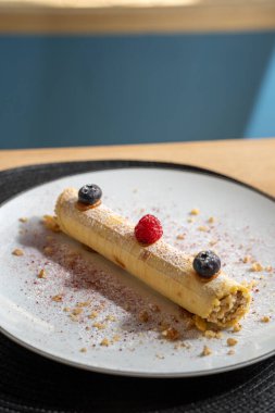 Beyaz tabakta ahududu ve yaban mersinli krep tatlısı..