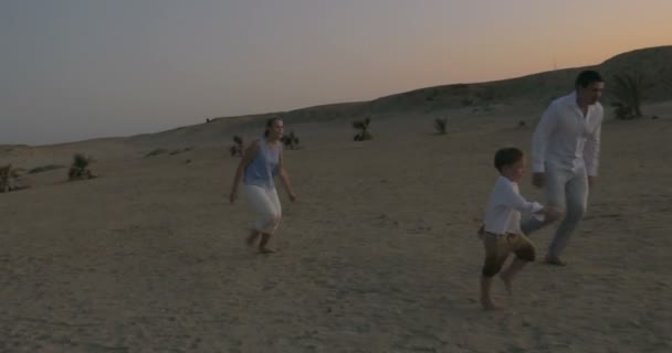 Родители и сын играют в футбол на пляже — стоковое видео