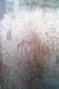 Paslı metalik bir yüzeye yakın çekim. Aşınma noktalarını ve yıpranmış doku detaylarını gösteriyor.