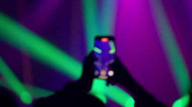 Siluet eller akıllı telefonu tutuyor yeşil lazer ışınları ve canlı elektronik müzik enerjisiyle çılgın bir konser yakalıyorlar.