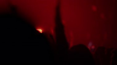 Seyirci siluetleri güçlü flaş ışıkları ve yüksek enerjili müzik anlarıyla yoğun konser sırasında ritm içinde alkışlıyorlar.