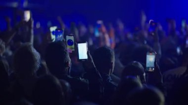 Yavaş çekim kalabalık dans ediyor ve canlı konser çekiyor. Parlak sahne ışıkları titreşiyor ve kolektif enerjiyi arttırıyor.