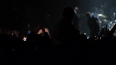 Yoğun seyircilerin üzerinde yetişkin omuzlarında oturan bir çocuğun silueti yanıp sönerken enerjik canlı müzik performansı sırasında renkler değişiyor.