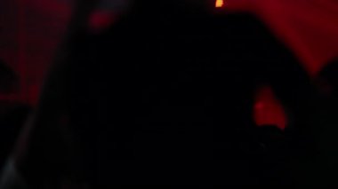 Kırmızı sahne ışıkları altında, bulanık kalabalık ve aydınlatma efektleriyle canlı konser.