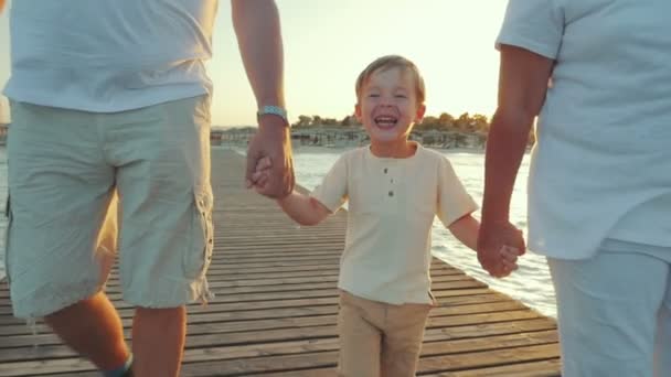 Niño feliz caminando con abuelos a lo largo del muelle al atardecer — Vídeos de Stock