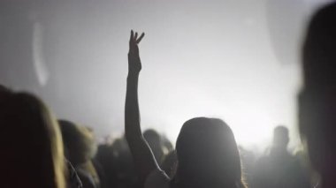 Canlı müzik etkinliği sırasında sahne ışığına uzanan arka ışıklandırılmış kalabalık duygusal konser atmosferi ve birlik hissi yaratıyor.