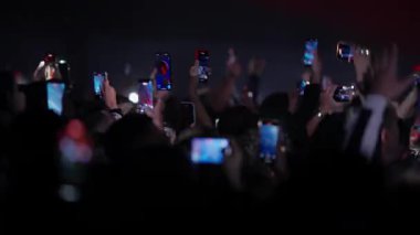 Seyirciler, karanlık konser salonlarında sahne ışıkları olan akıllı telefonlarda canlı müzik performansı sergiliyor.