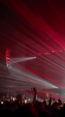 Yükselen ellerin dikey görüntüsü ve parlayan telefon ekranları canlı müzik anını yakalıyor.