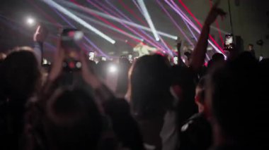 Konser kalabalığı akıllı telefonları kaldırıyor ve lazer sahne ışıkları altında canlı performans çekerken zıplıyorlar.